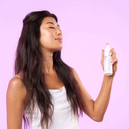 Woman spraying calming facial spray on face
