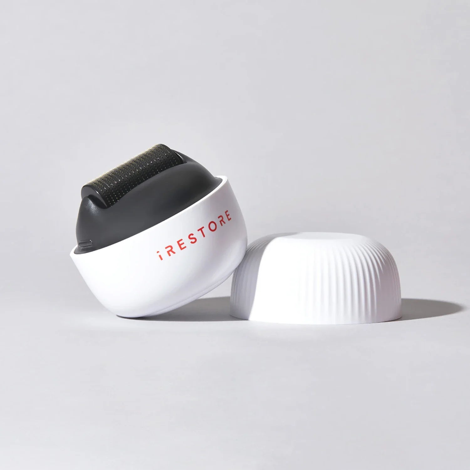 Image of the ScalpStim Derma Roller placed on top of a table with its cap beside it.