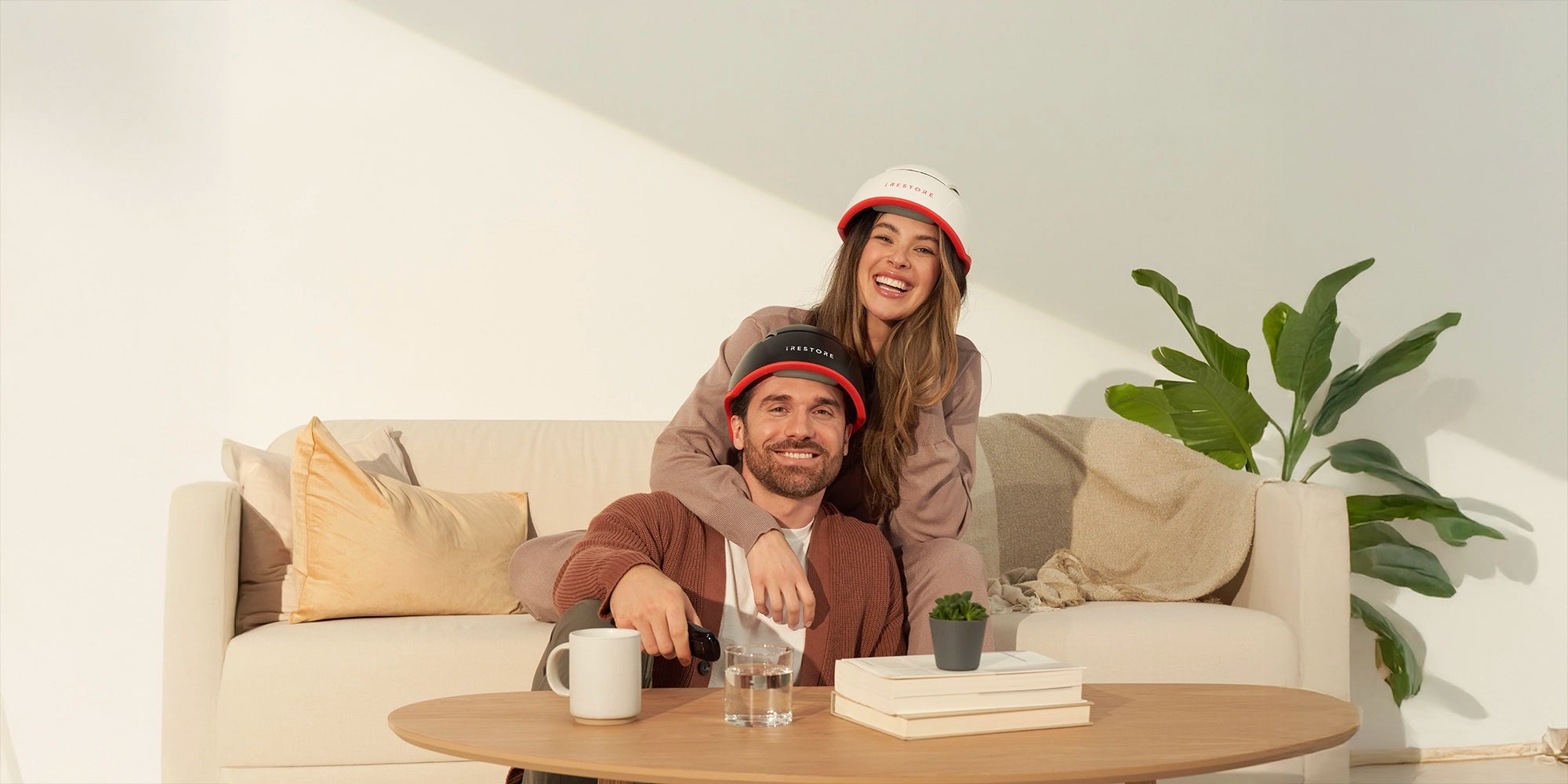 man and woman wearing irestore hair devices on sofa